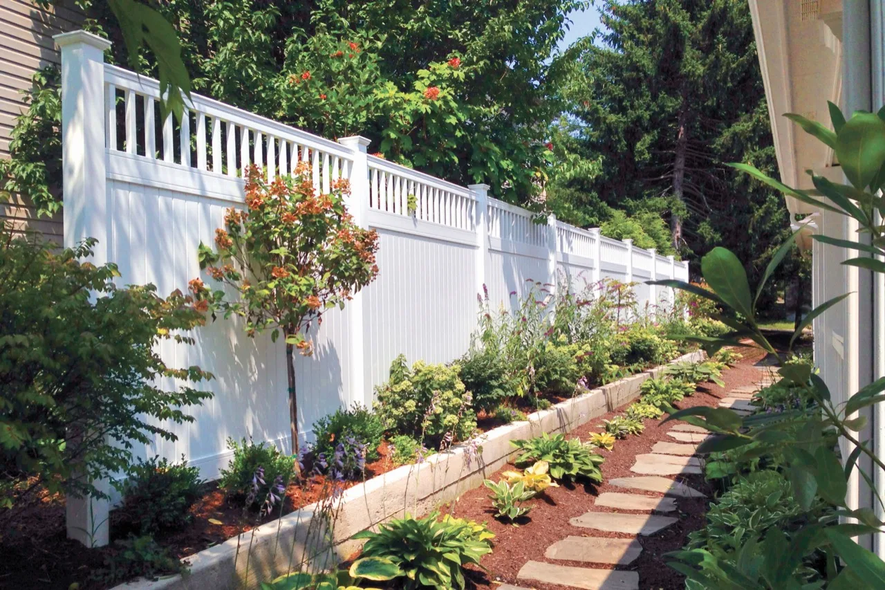 White vinyl privacy fence on a landscaped property in southern Louisiana